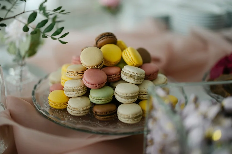 Colorful macarons stacked on a glass plate at a dessert table.