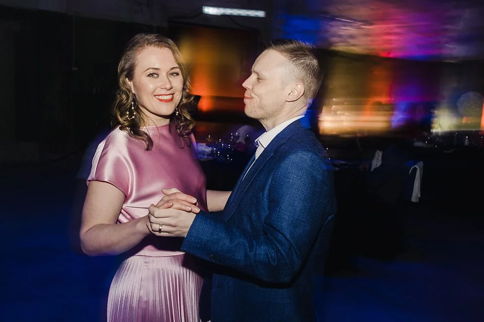 A couple dancing at an event with colorful blurred background lights.