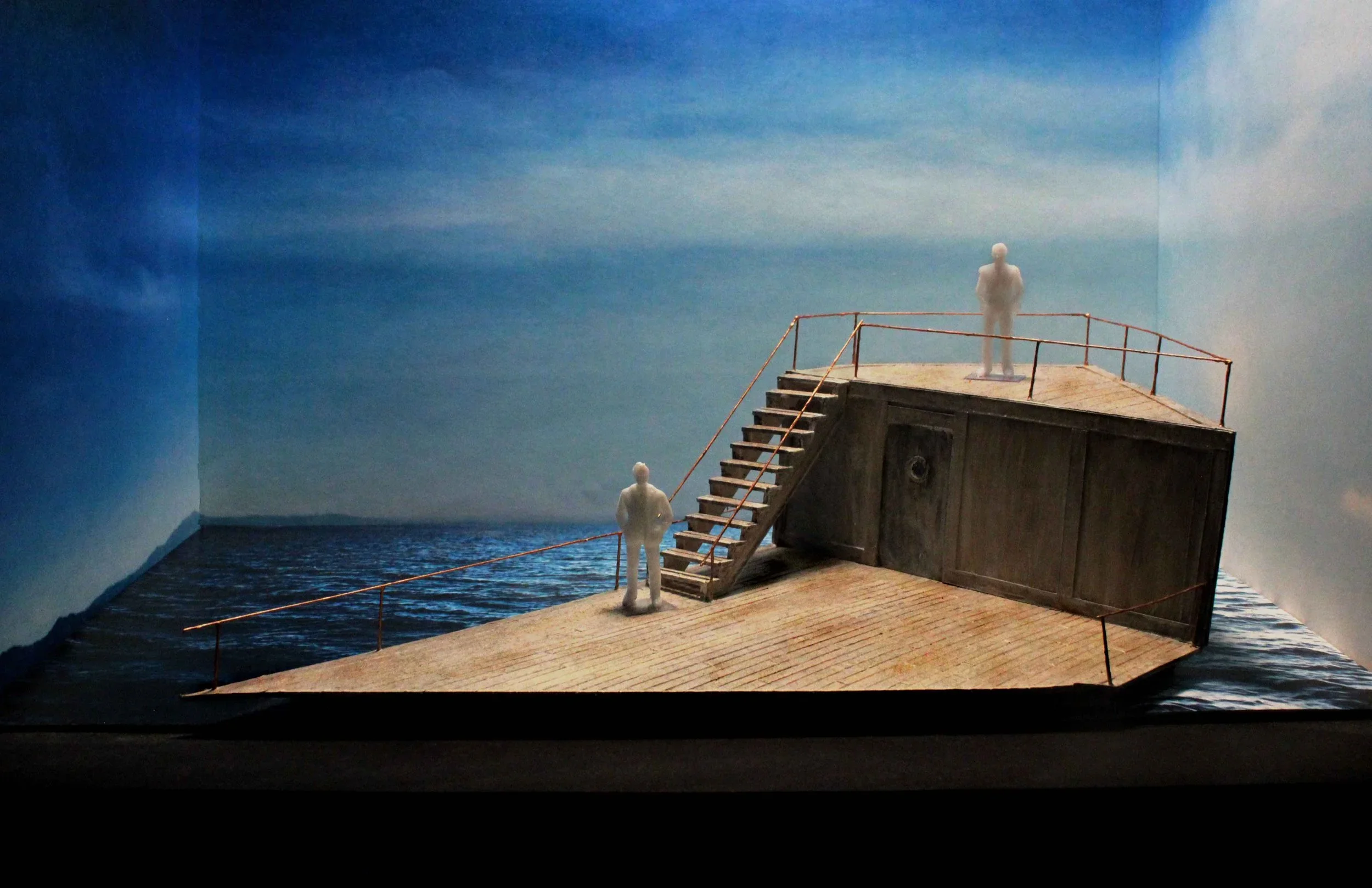 Two white, plastic figures stand on the upper and lower decks of a ship adrift at sea. Three sky-covered walls define the space.