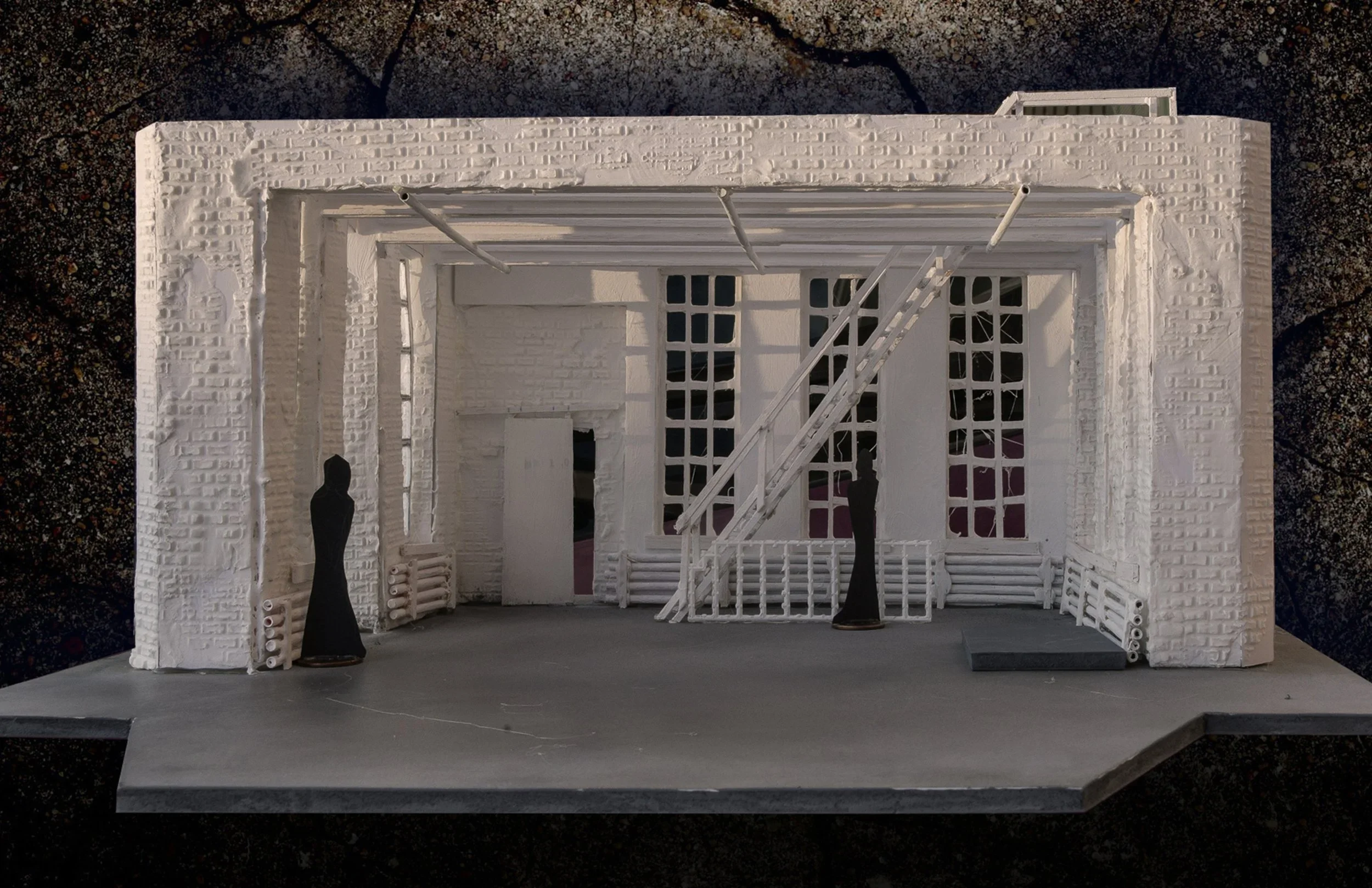 Two silhouetted figures inhabit a whitewashed-brick, industrial space, in front of a cracked concrete wall.