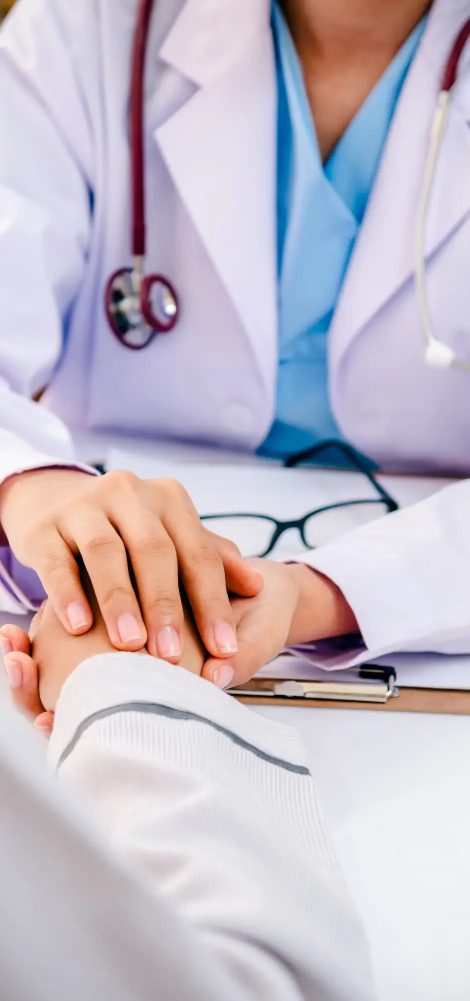 Nurse practitioner holding a patient's hand during a medical consultation, representing compassionate, patient-centred primary care, preventive healthcare, and collaborative treatment planning.