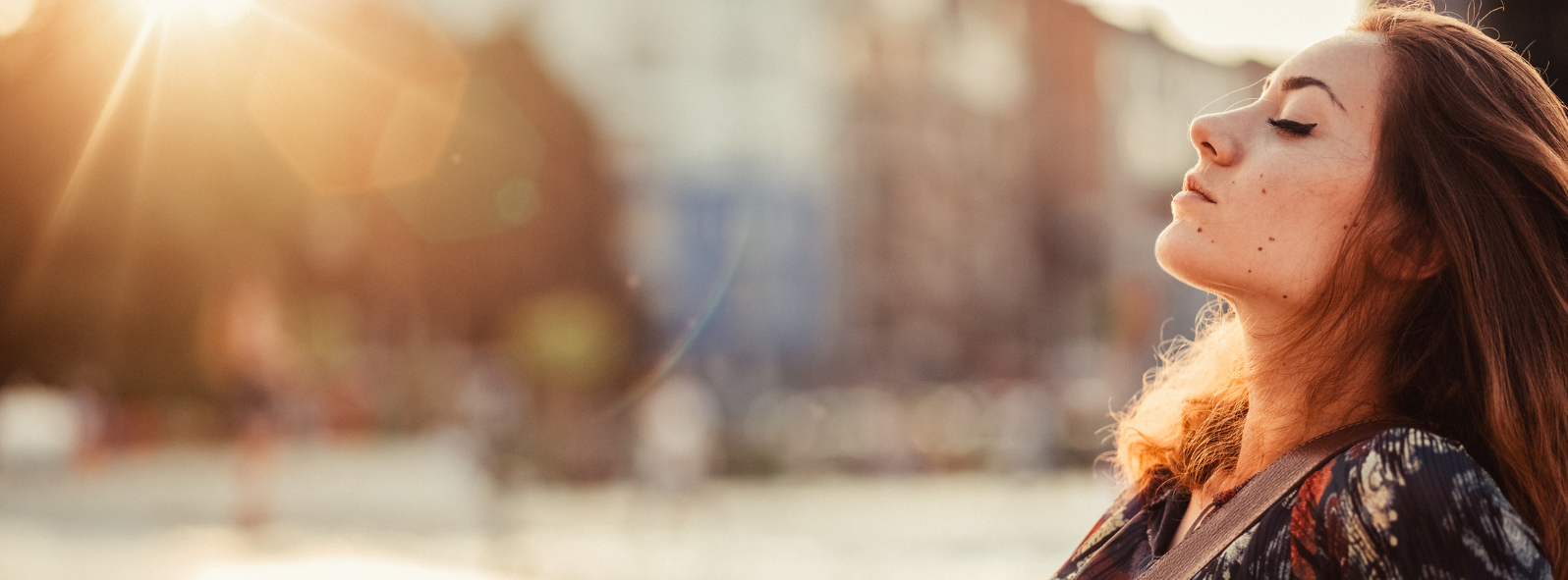 Woman standing outdoors with eyes closed in warm sunlight, representing emotional wellness, stress relief, and mental health support at a therapy and counselling clinic in East St. Paul.