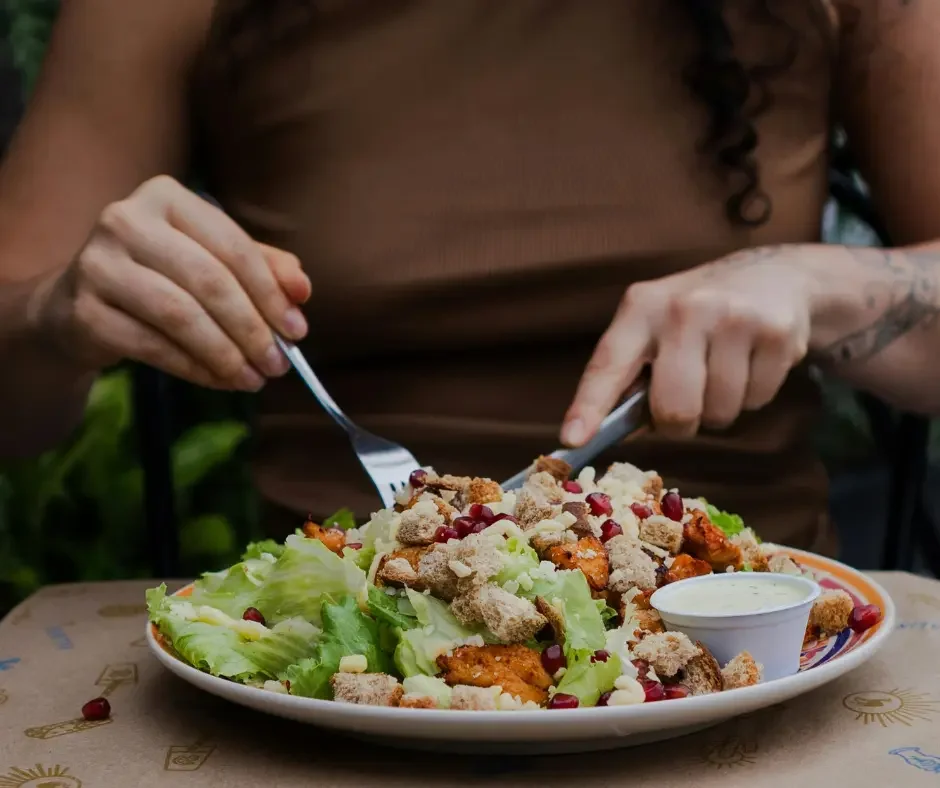 Woman eating a fresh, nutrient-rich salad, representing nutrition and healthy lifestyle support during fertility and preconception care.