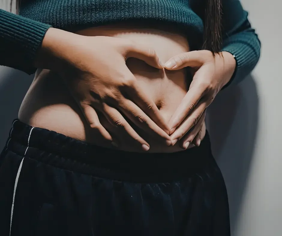 Pregnant woman holding her abdomen, representing fertility and preconception support at True Health Integrative Clinic.