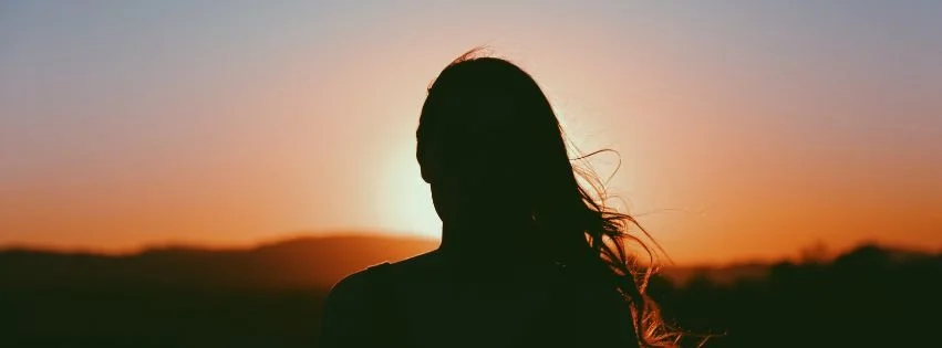 Silhouette of a woman standing outdoors at sunset, representing women’s hormonal and reproductive health.