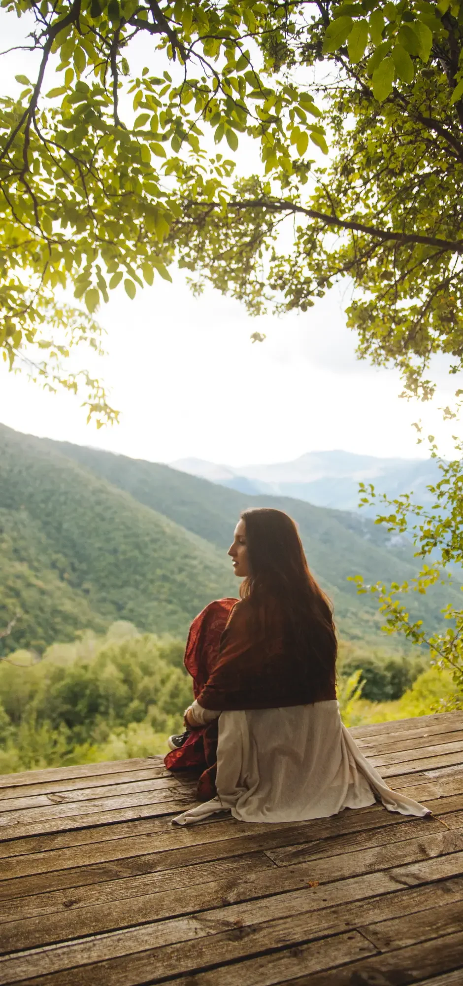 Person sitting peacefully in nature overlooking a mountain landscape, representing the holistic, whole-person approach of naturopathic medicine and the connection between health, environment, and wellbeing.