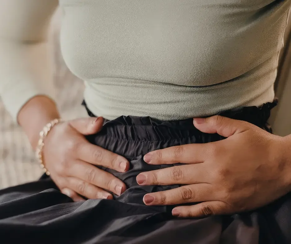 Close-up of a person holding their lower abdomen, illustrating pelvic pain and discomfort associated with endometriosis.