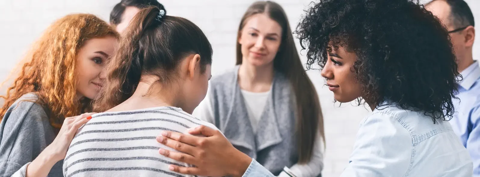 Supportive group therapy session with individuals offering comfort and connection in a mental health counselling setting focused on emotional wellness and healing in East St. Paul.