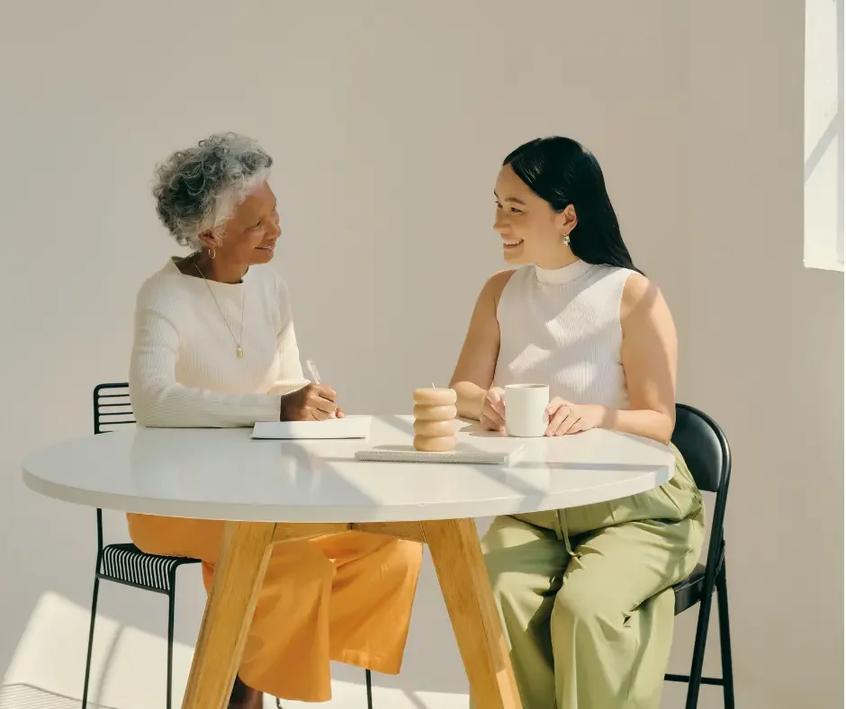 Two women sitting together at a table, representing a supportive, personalized approach to women’s hormonal and metabolic health.