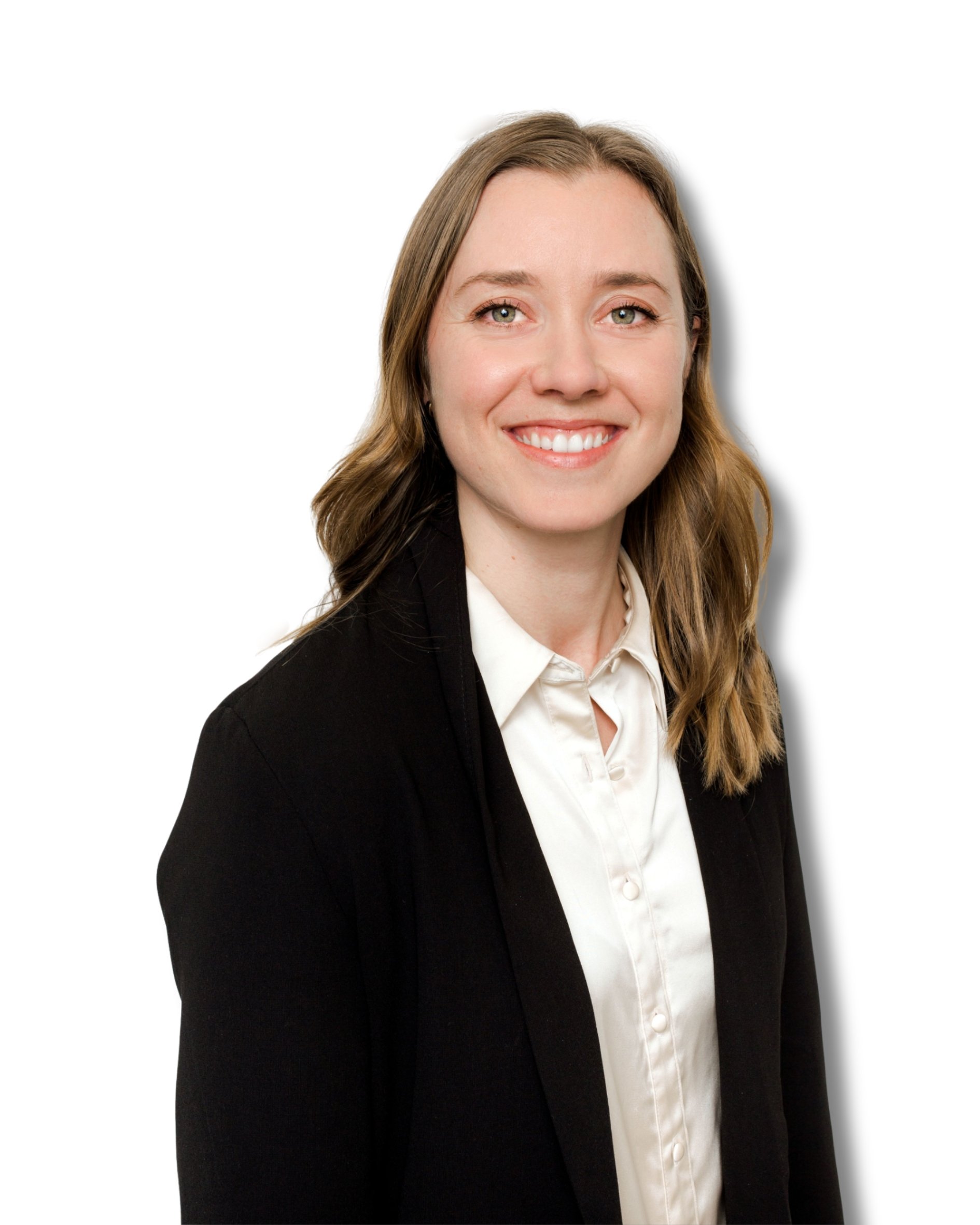 Portrait of a young woman with light skin, long wavy brown hair, wearing a black blazer and white shirt, smiling against a white background.
