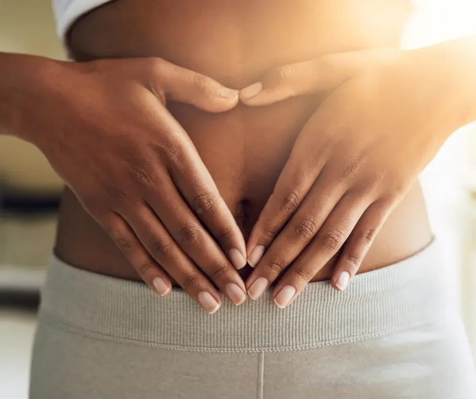 Close-up of a person gently placing their hands over their lower abdomen, representing pelvic discomfort, abdominal pain, and endometriosis symptoms.