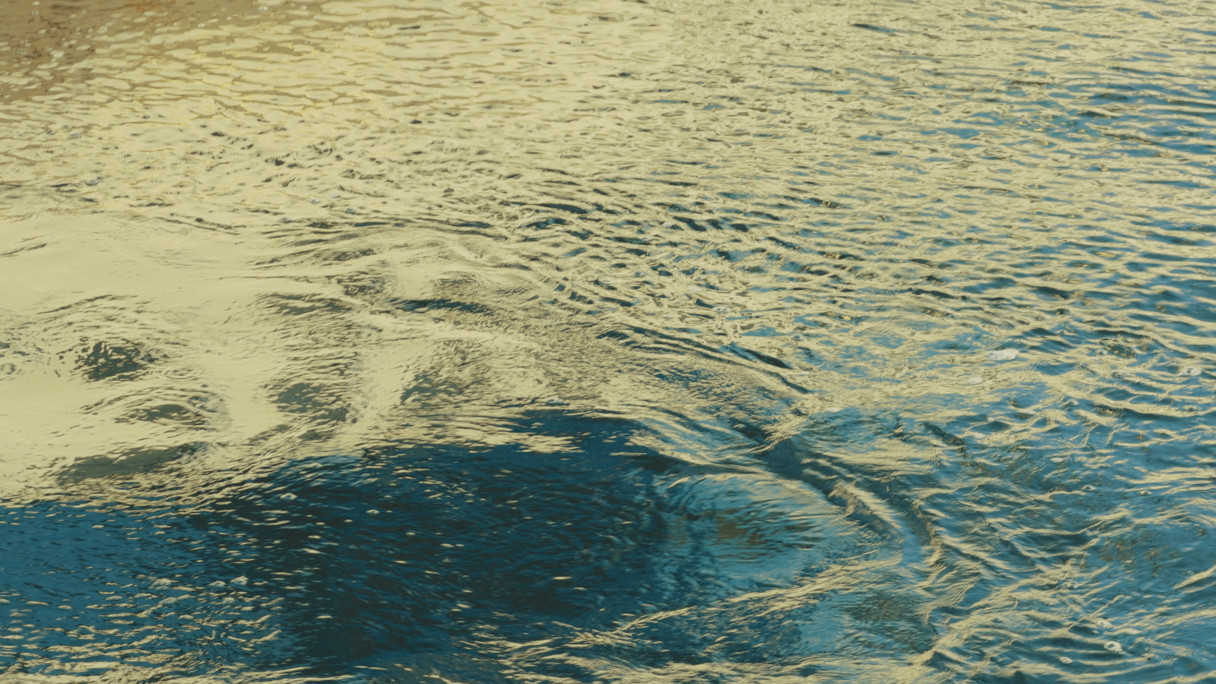 Close-up of rippling water with reflections of sunlight.