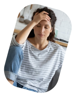 Young woman sitting at a desk with her hand on her forehead, looking concerned or stressed.