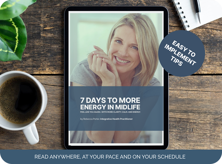 A tablet displaying a booklet titled "7 Days to More Energy in Midlife" with a smiling woman on the cover, placed on a wooden table next to a coffee mug, a small green plant, a notepad, and a pen.