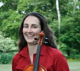 Woman smiling outdoors holding a violin