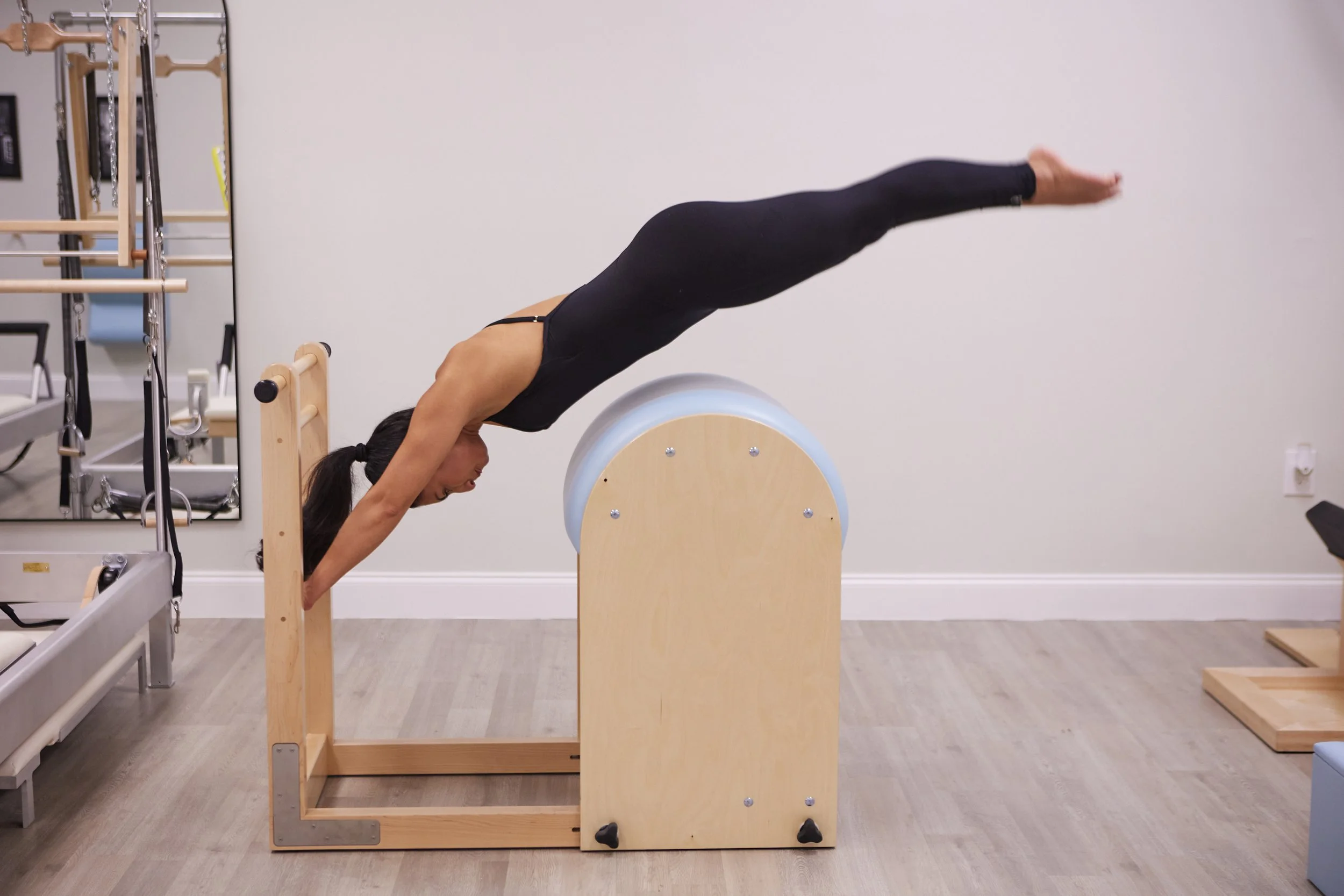 Woman performing a Pilates exercise on a pilates arc in a fitness studio.