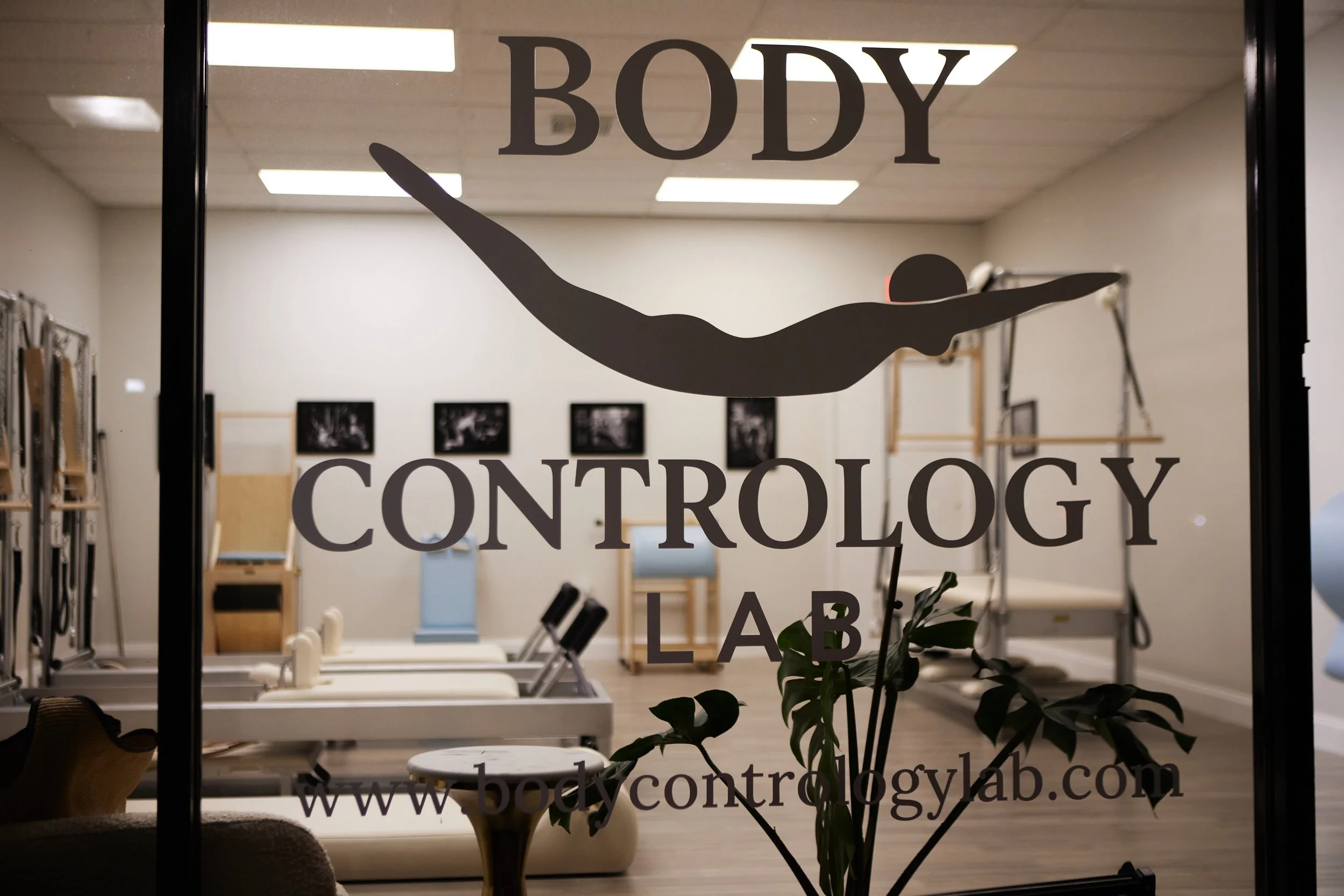 Door of a body controlology lab with logo of a diver in mid-air and text 'Body Controlology Lab' and website 'bodycontrologylab.com'.