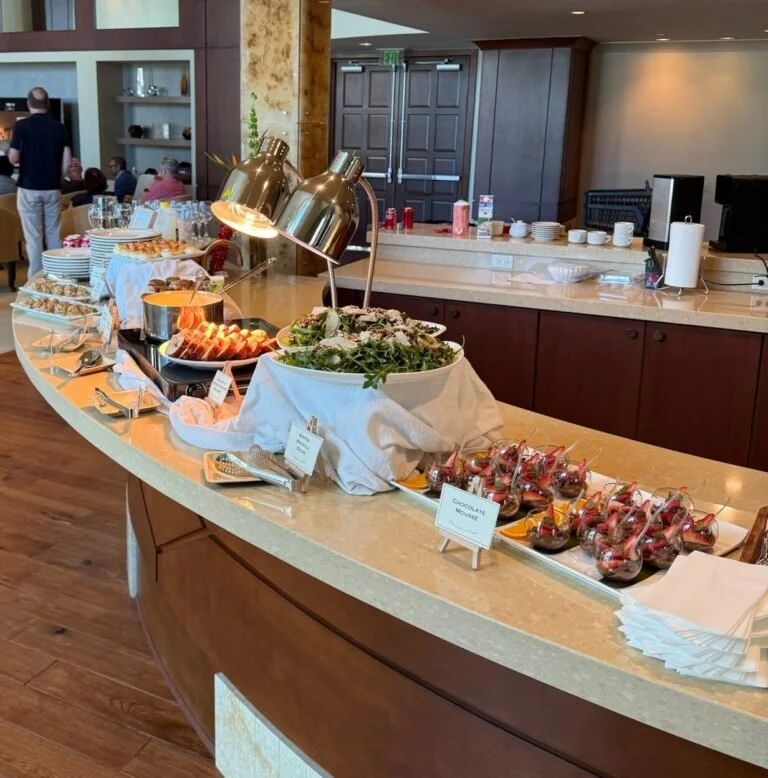 Buffet table with salads, desserts, and condiments at a dining area.