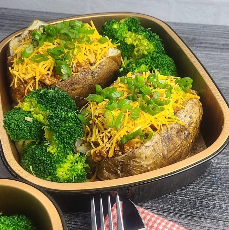 Baked sweet potatoes topped with shredded cheese and chopped green onions, served with steamed broccoli.