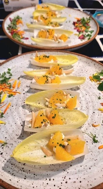 Eggplant slices topped with mango, nuts, and herbs on speckled ceramic plates.
