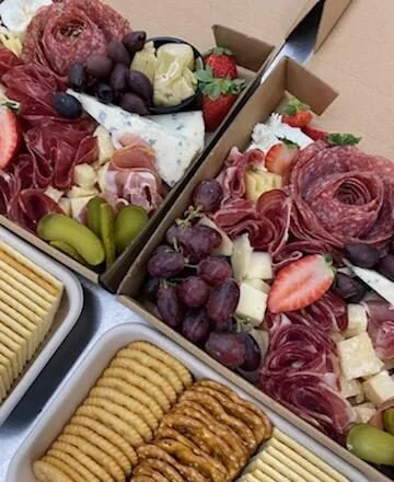 Charcuterie boards with cured meats, cheeses, grapes, strawberries, and crackers.