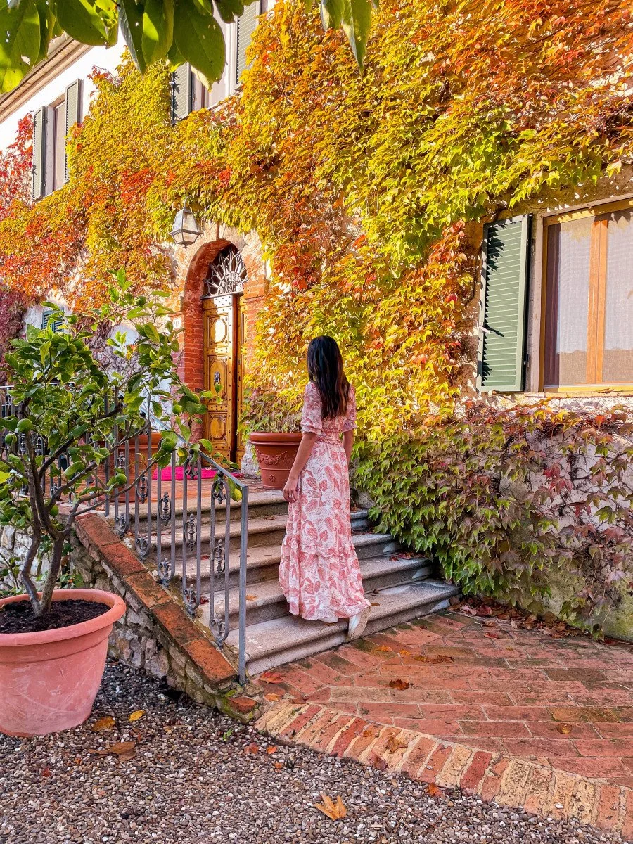 woman on stairs in maxi dress surrounded by autumn foilage