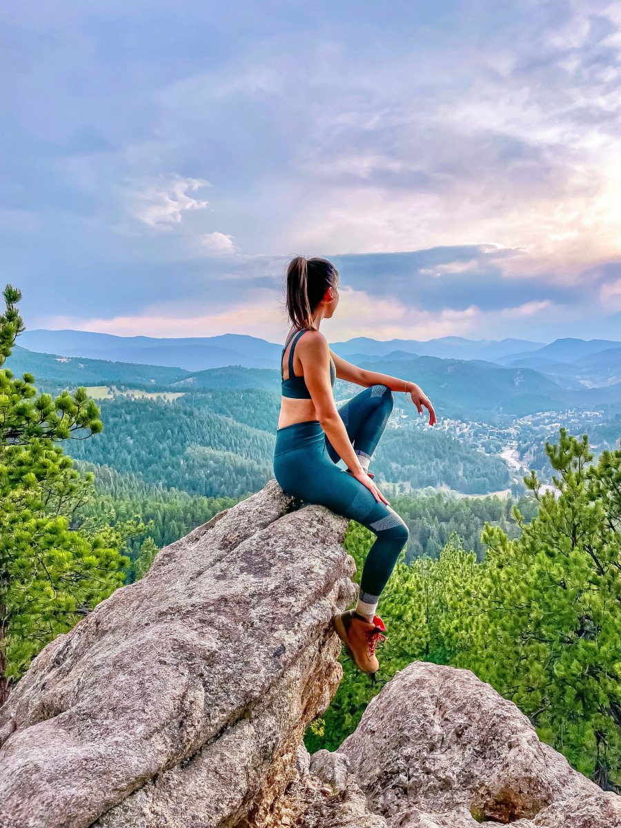 woman sitting on top of rock on mountain