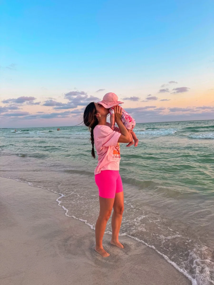 woman kissing baby at beach