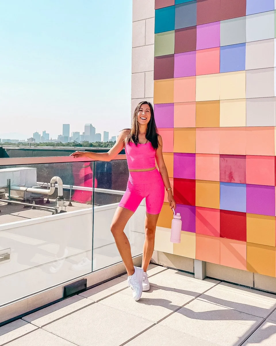 woman standing on rooftop in front of multicolored wall
