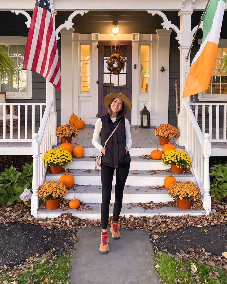 girl posing in front of porch with pumpkins and mums