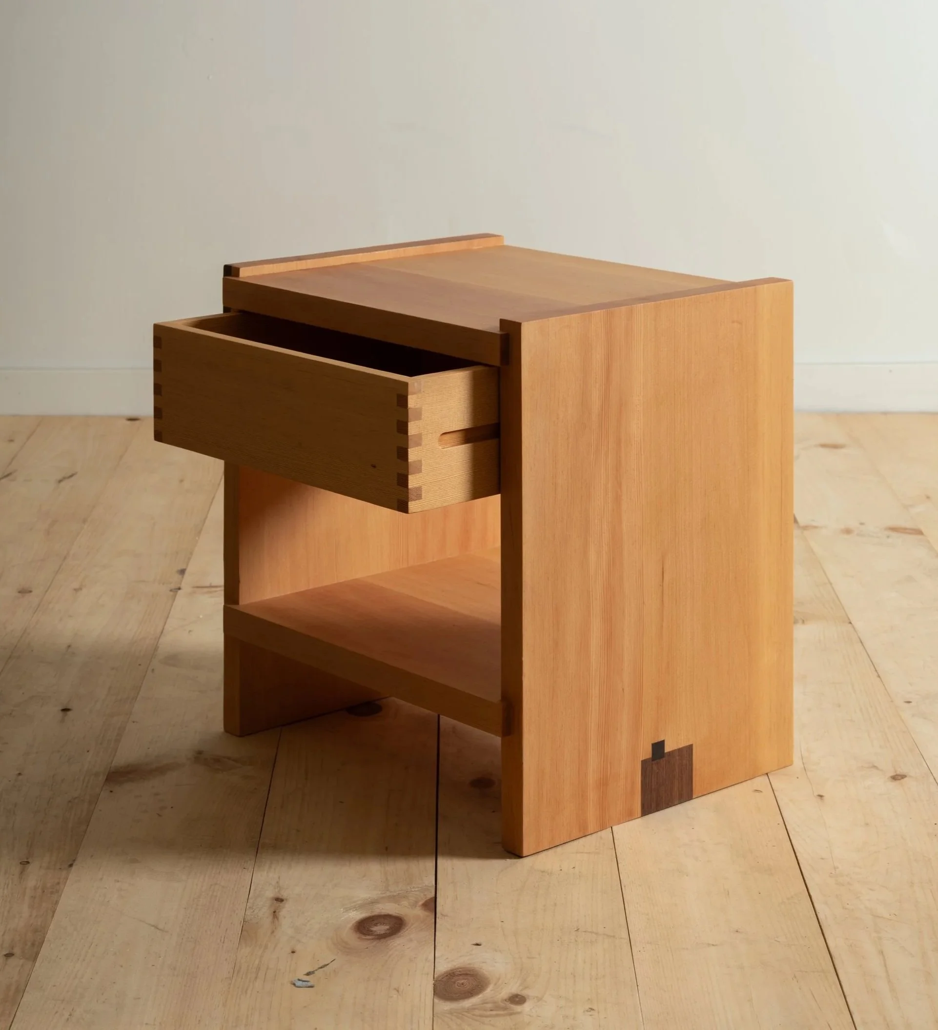 Pair of minimalist wooden nightstands with open shelves and dovetail joinery, set on a concrete floor against a white background.