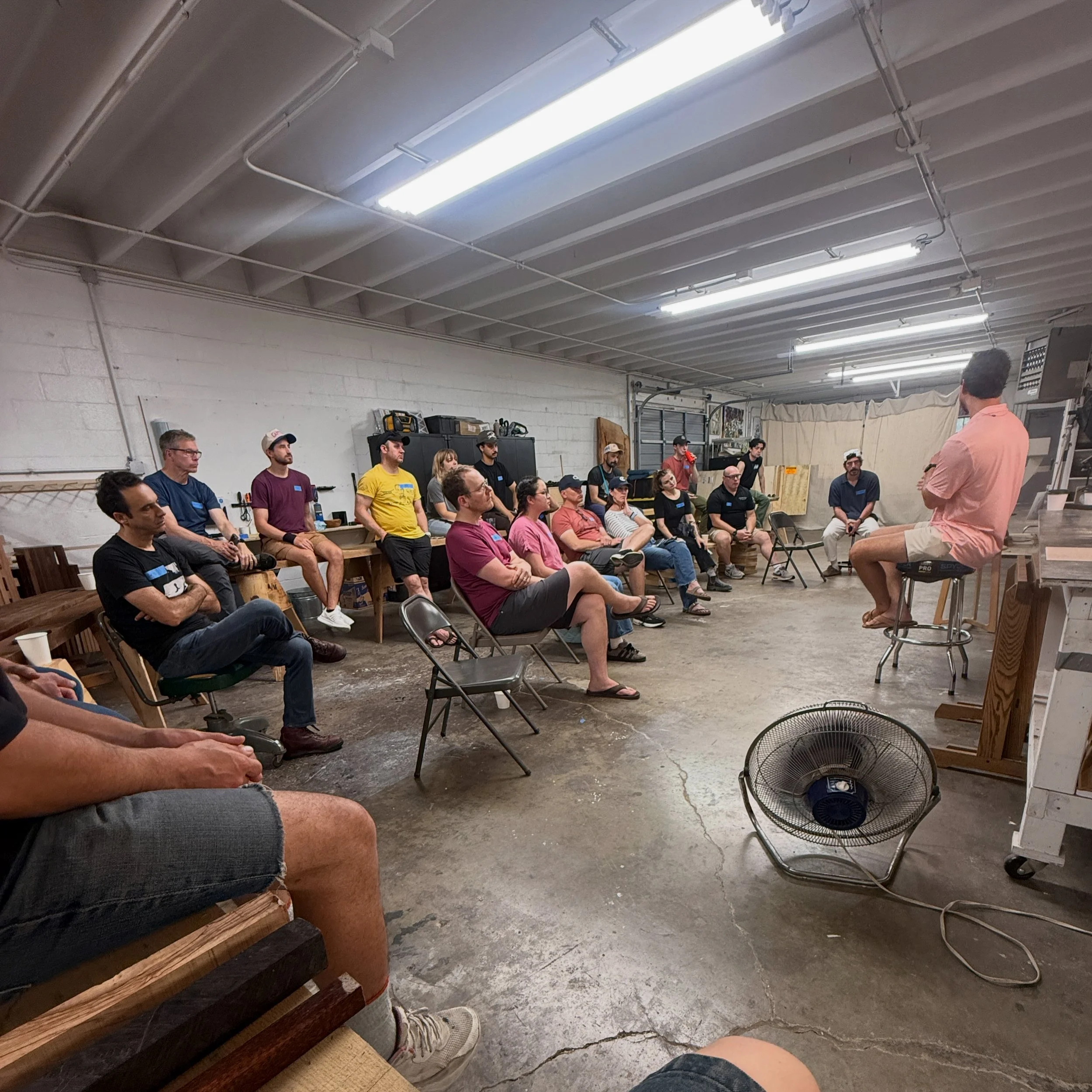 A landscape with snow-capped mountains in the background and a few modern buildings on a grassy hill in the foreground.