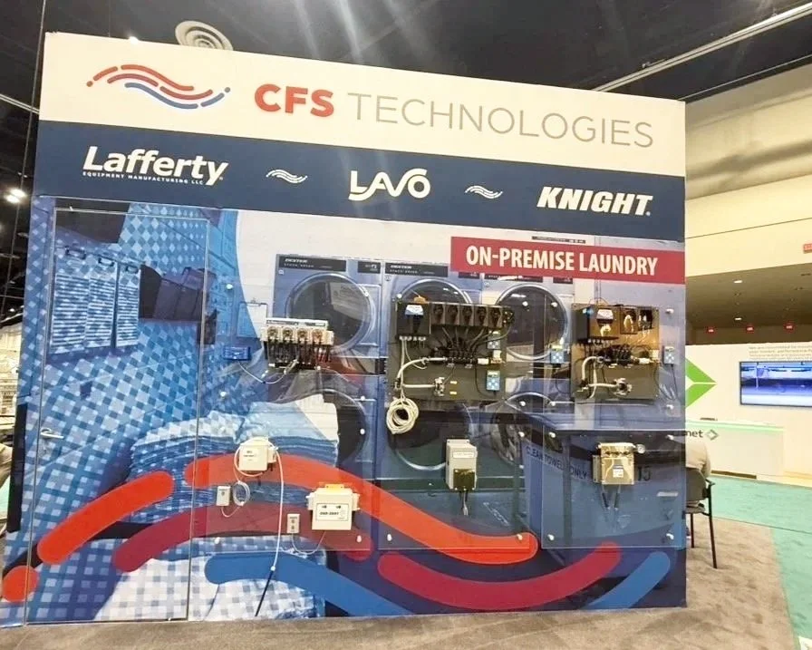 Exhibit booth display for CFS Technologies showing laundry equipment and electrical components, with logos of Lafferty, LAVO, and Knight, at an indoor trade show.