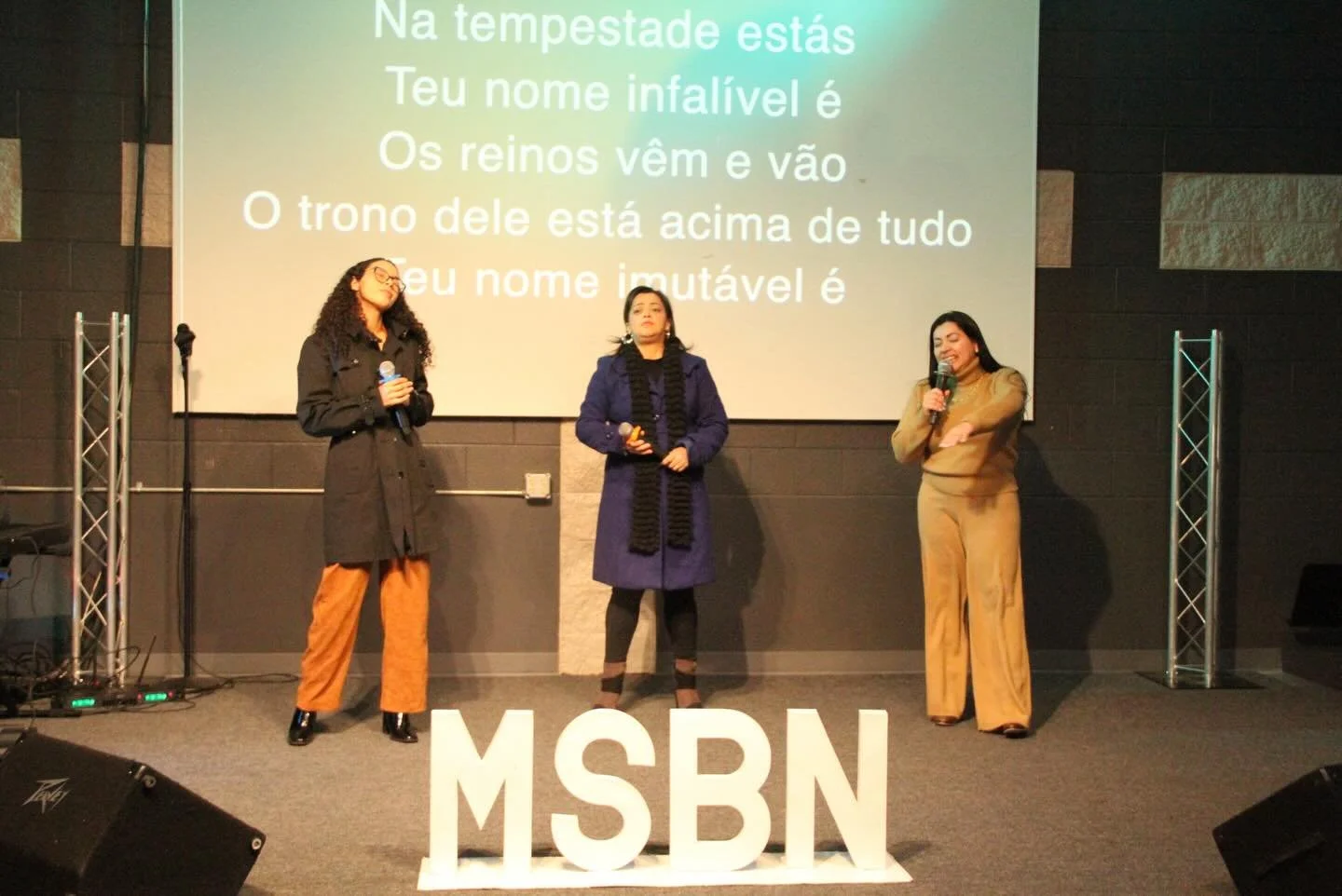 Group of five people in a storage room filled with sports and playground equipment, smiling and holding orange and black balls.