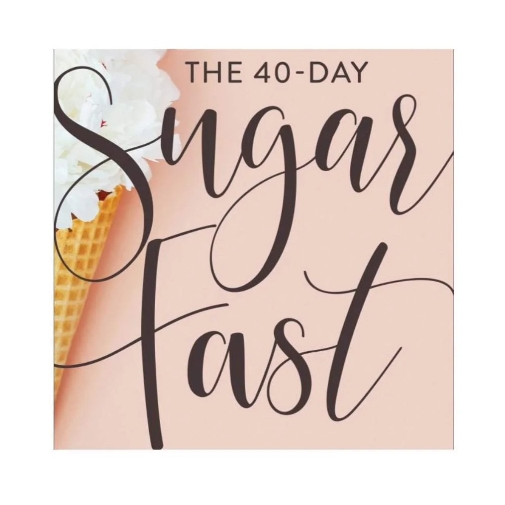 A group of children sitting on the floor watching a man and a young boy perform on stage, with colorful large posters in the background, in a church or auditorium setting.