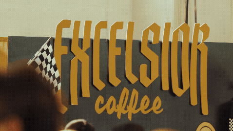 Sign that reads 'FEXELSIOR coffee' with a checkered flag design on the side.