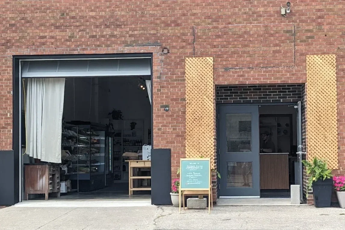 A brick storefront in Toronto with an open garage-style door and potted flowers, representing local small businesses and neighbourhood retail.