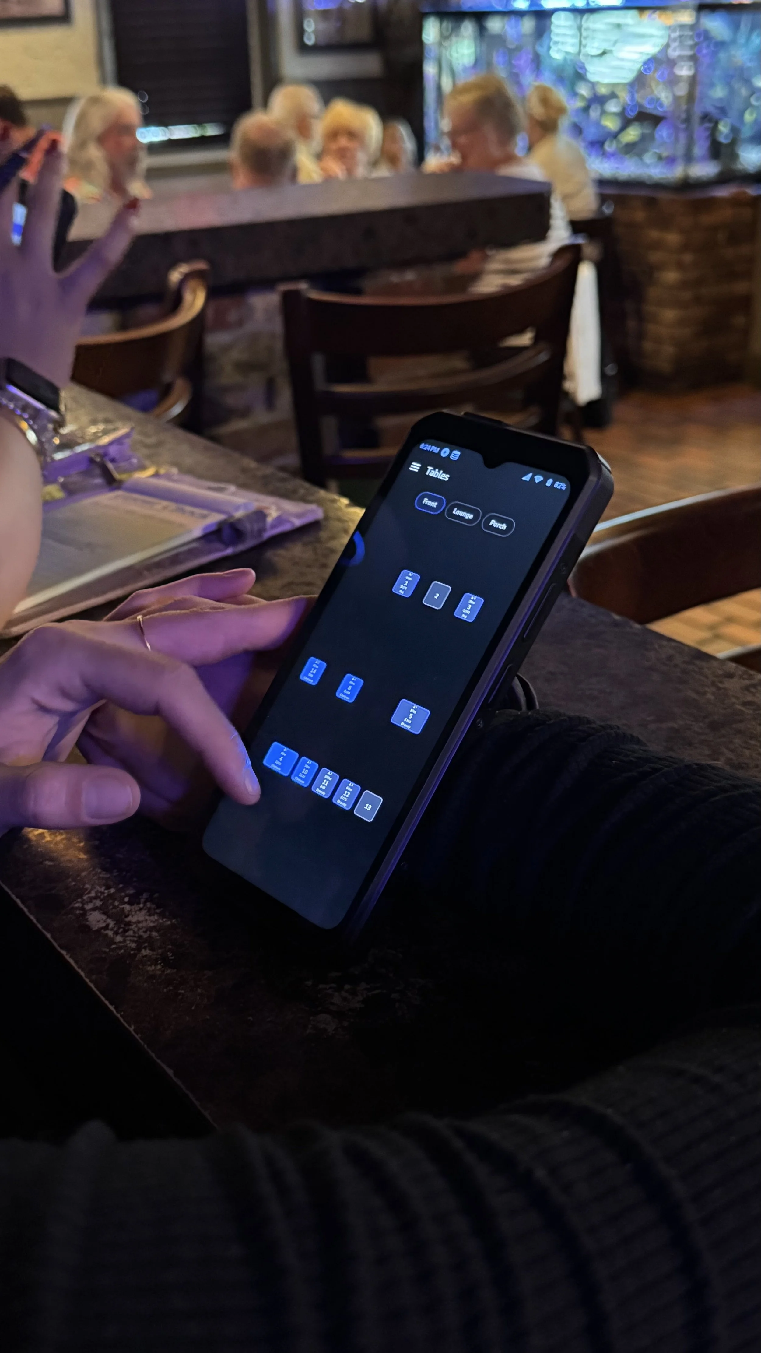 SkyTab Air handheld in a servers hands with screen showing a restaurant table layout.