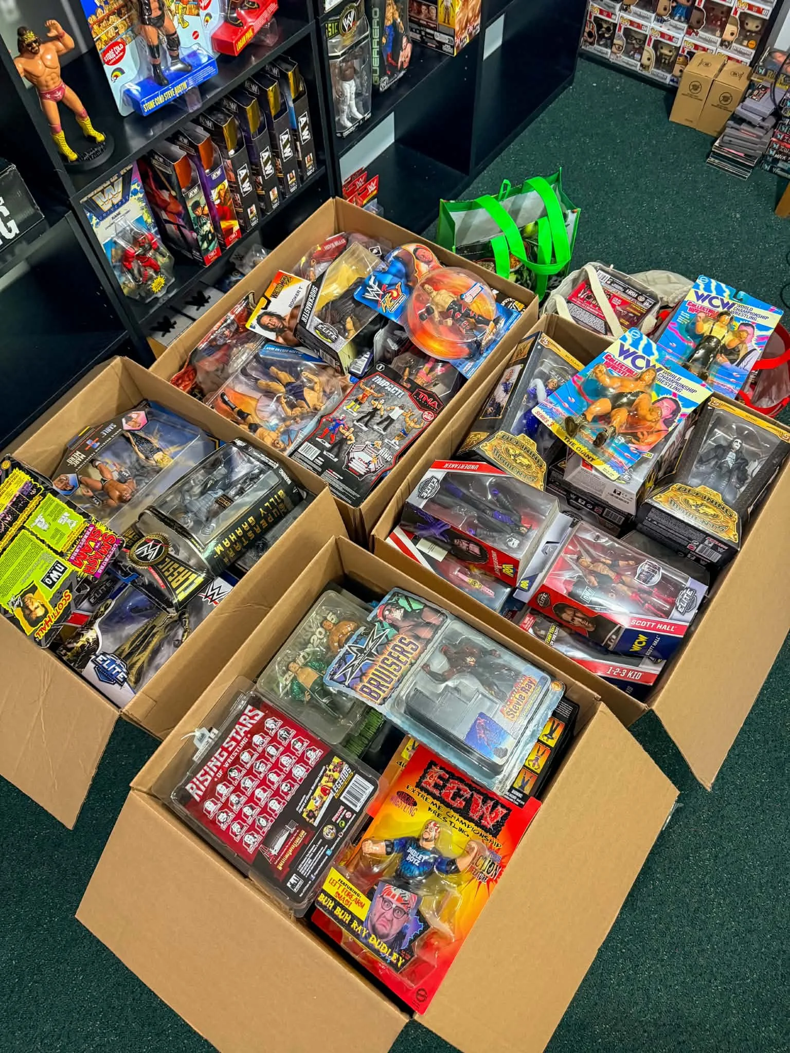 Top view of multiple cardboard boxes and shelves filled with wrestling action figures and toys in packaging.