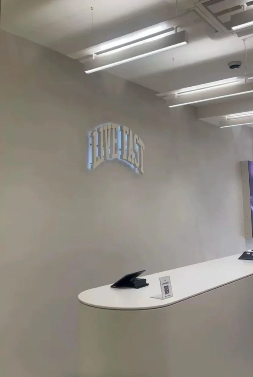 Ein Empfangstresen in einem modernen Büro mit einem Telefon und einem QR-Code, an der Wand ist ein beleuchtetes Schild mit der Aufschrift 'Future's'.