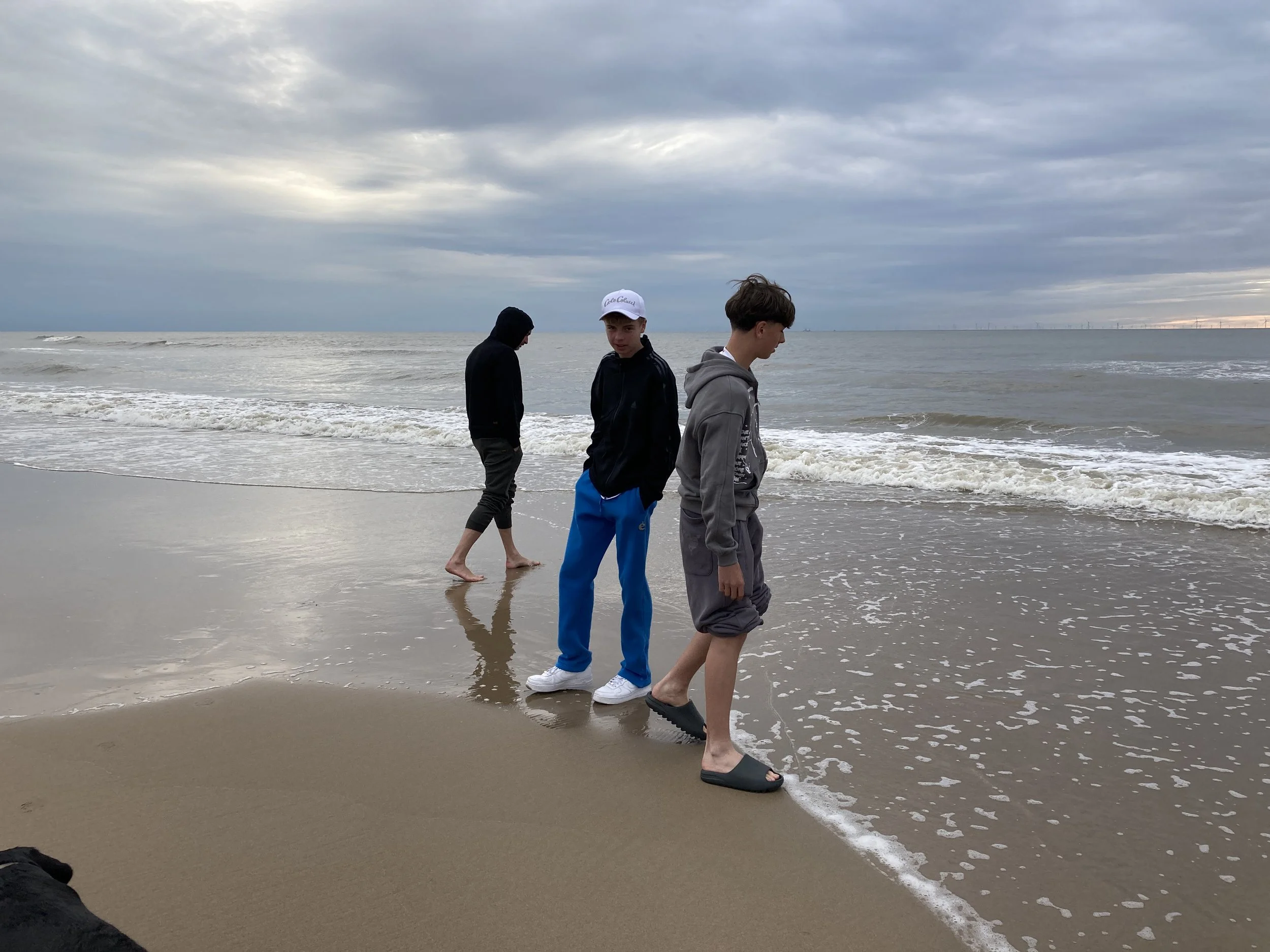 Drei Jugendliche stehen am Strand, beobachte das Meer bei wolkigem Himmel.