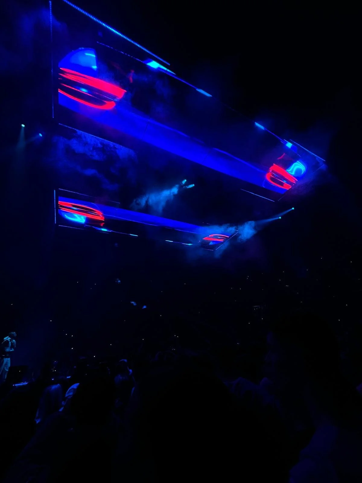 Finn war beim Luciano Konzert in Köln 2024. Dunkle Konzerthalle mit blauer und roter Neon-Beleuchtung, Publikum im Vordergrund, große Bildschirme und Lichteffekte an der Decke.