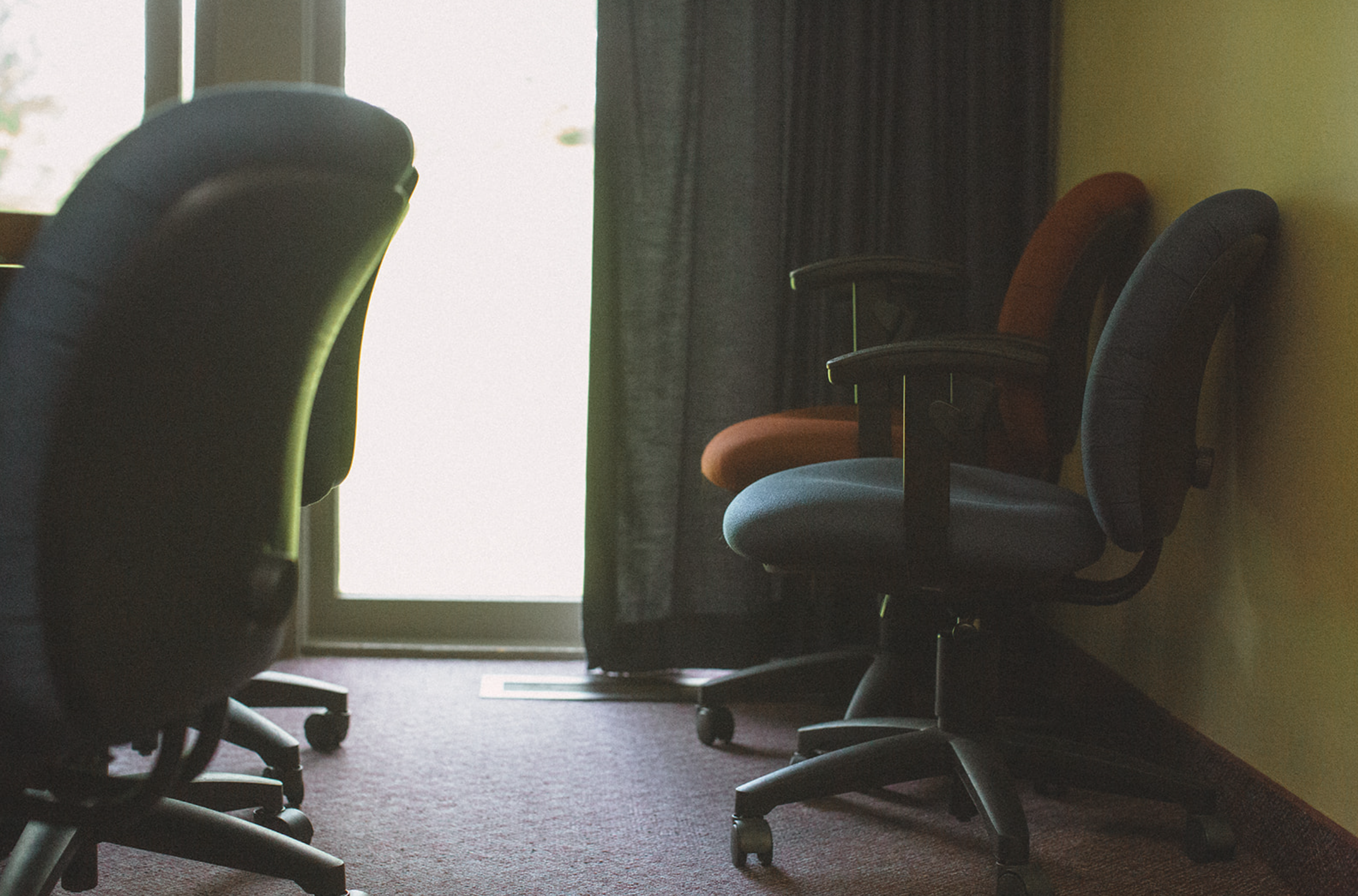 Empty office chairs in a room with a window and sunlight