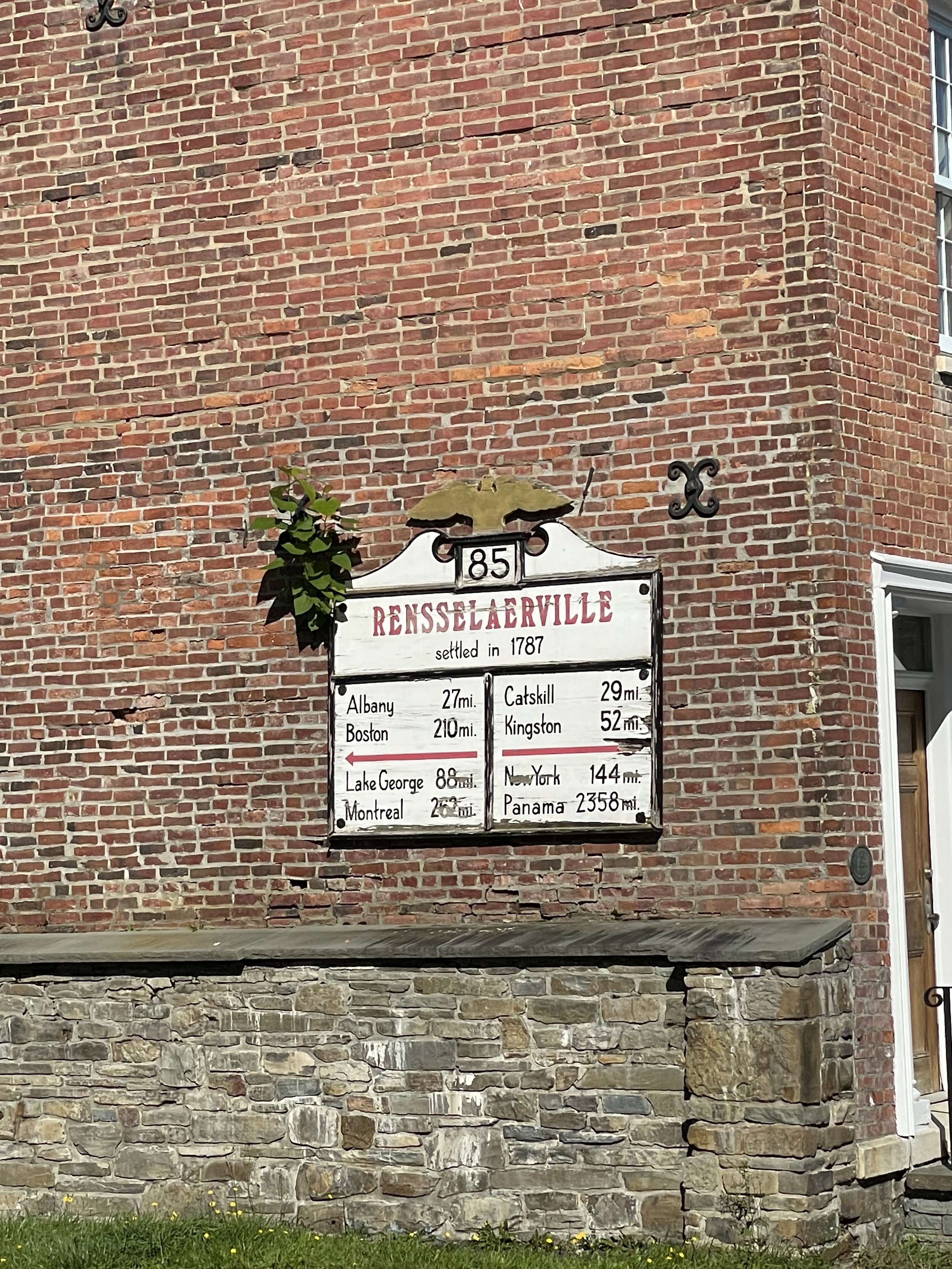 Historical signboard on a brick wall of Reisselaerville, settled in 1787, showing distances to Albany, Boston, Lake George, Montreal, Catskill, Kingston, New York, and Panama.