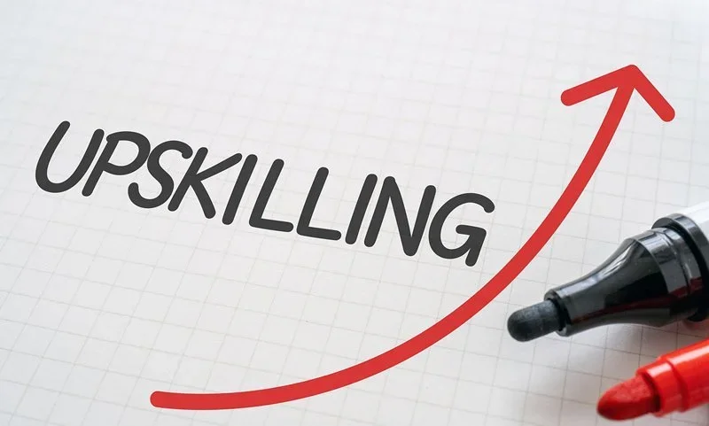 A red arrow labeled “Upskilling” rising upward, symbolizing executive awareness training and competitive business growth.