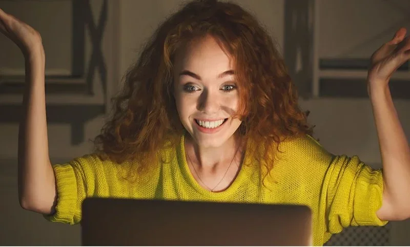 A smiling professional watching a training video on a laptop, symbolizing on-demand learning and scalable skill-building through SharePoint.