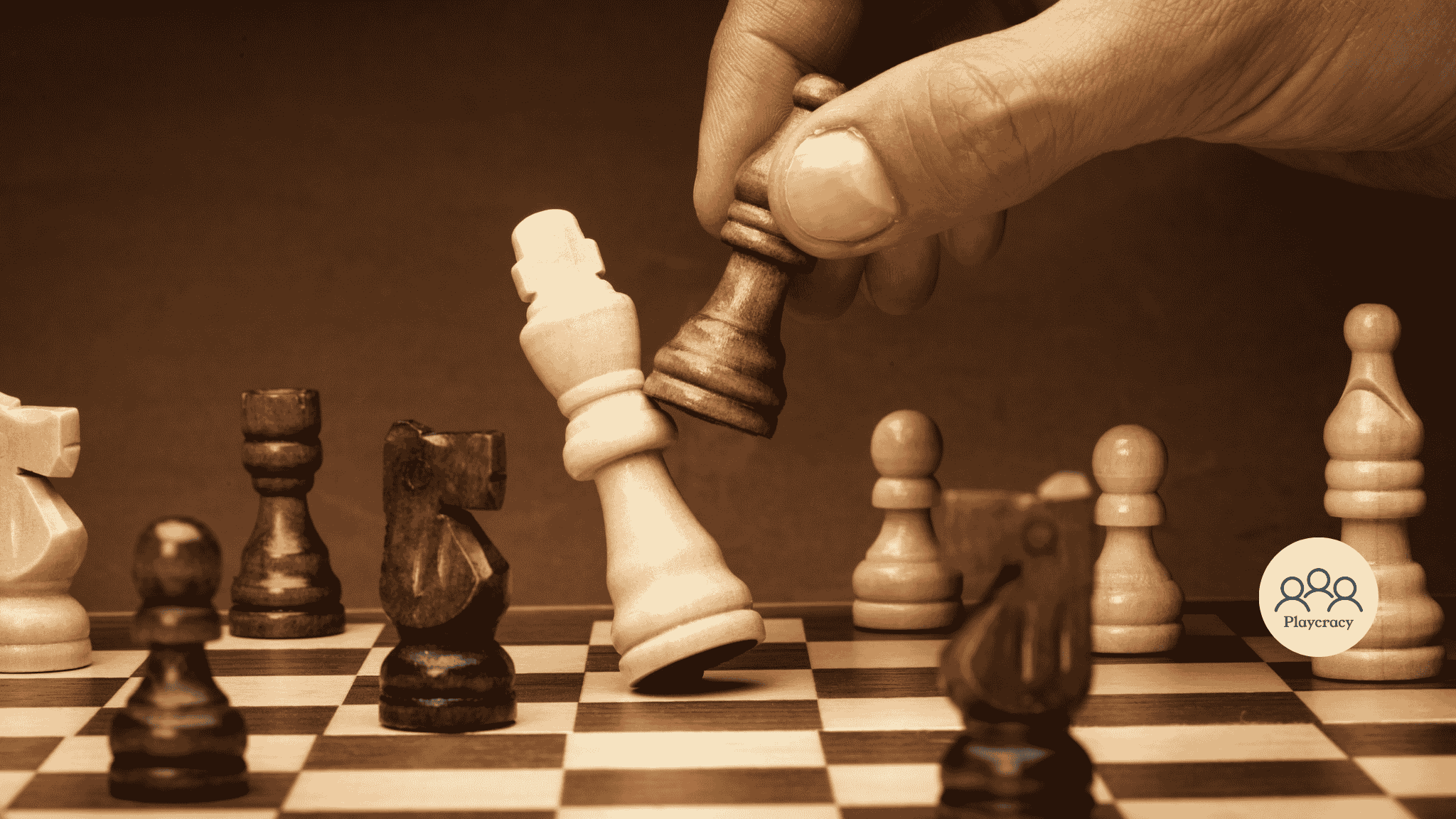Fingers hold a chess pawn about to throw the opponent's king on the board, thus ending the game. The image has a brown tone.