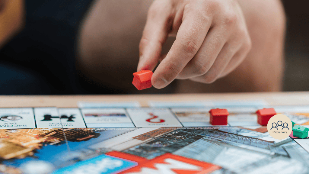 A hand places a hotel of the game Monopoly onto the board