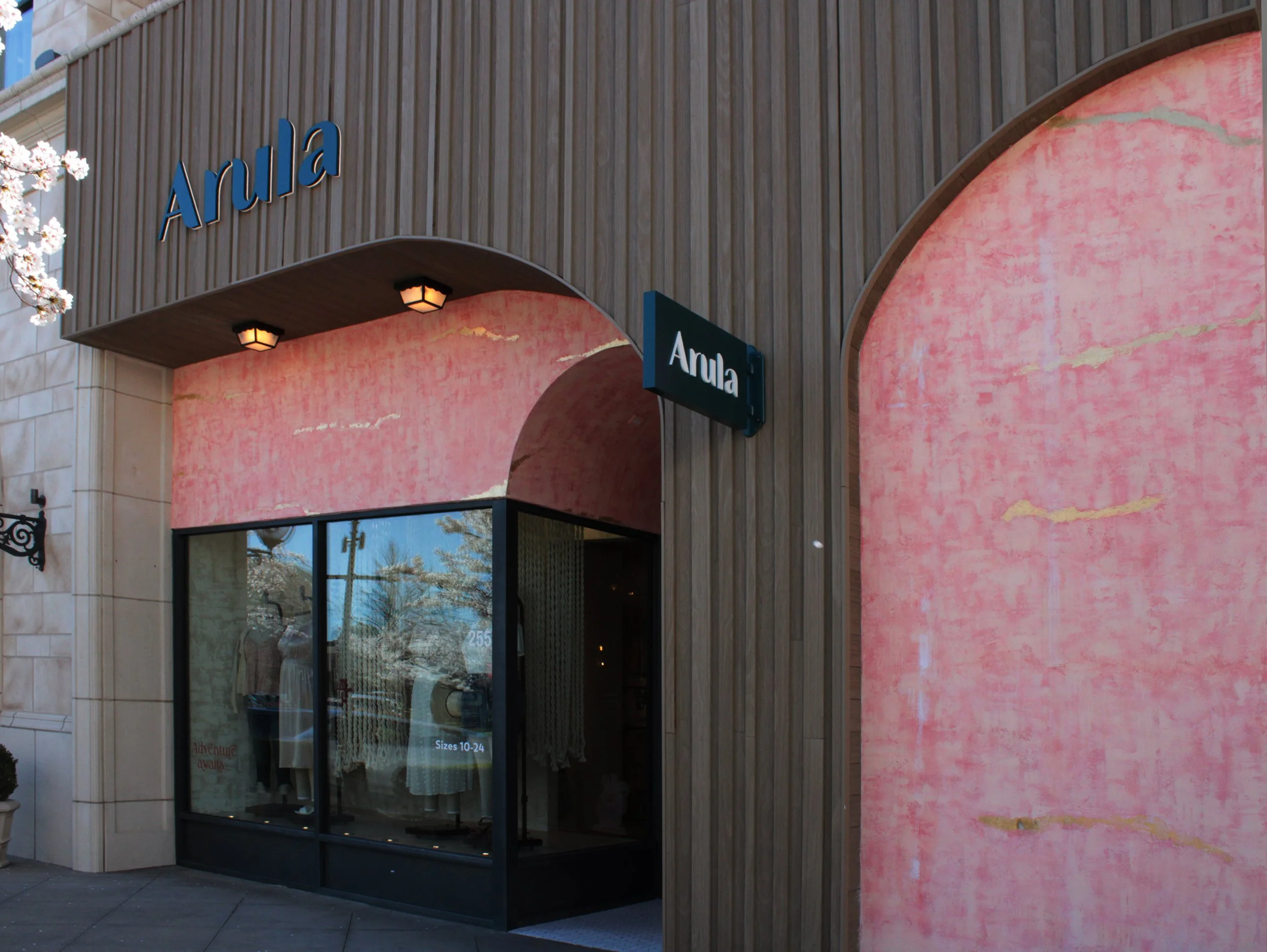 storefront with the sign 'Anula', pink textured walls, and glass windows displaying dresses inside.