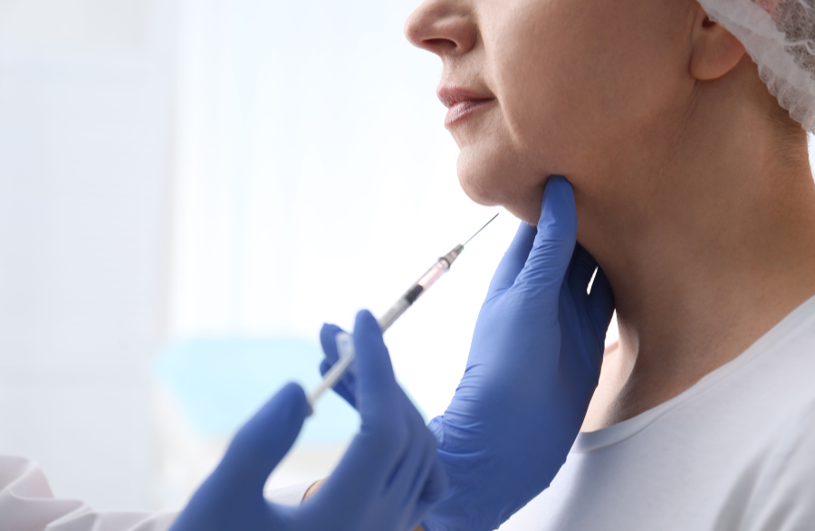 A healthcare professional prepares to give a woman a facial injection in a clinical setting.